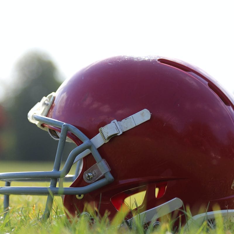 Red football helmet on grass field during daytime