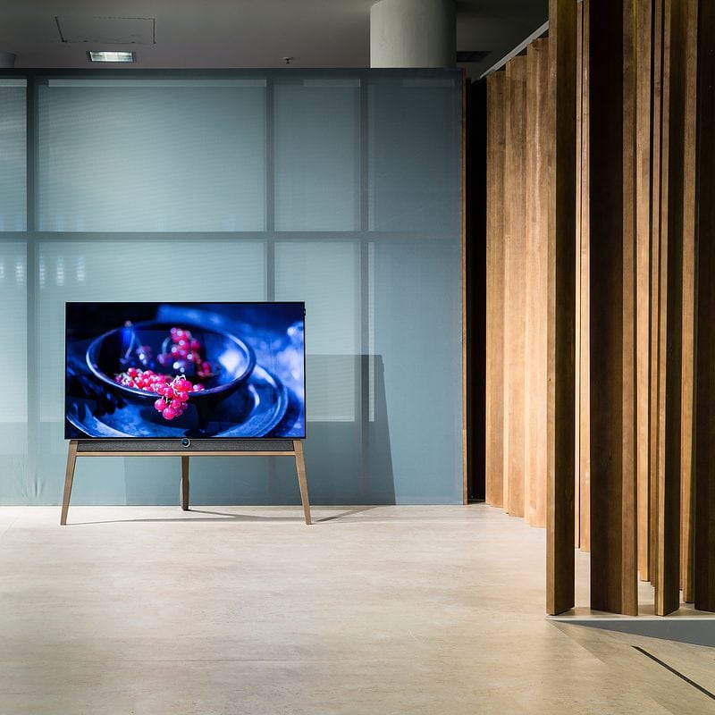 Modern TV on stand in stylish interior with wooden paneling and bench