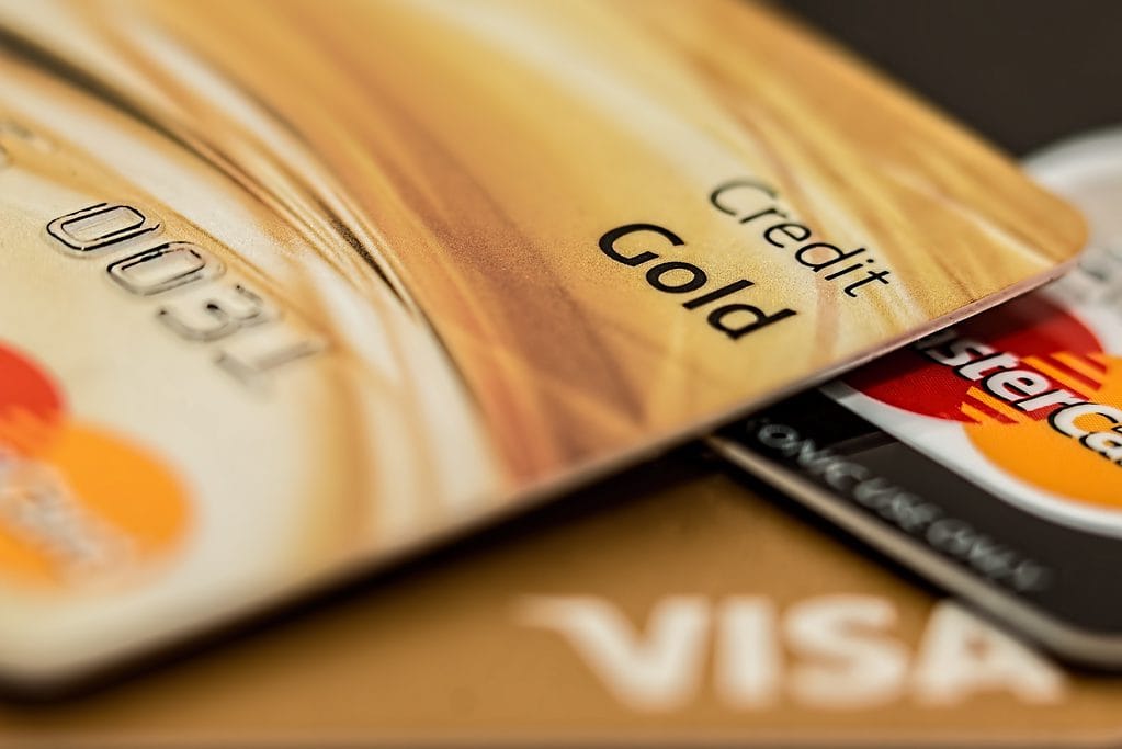 Close-up of gold credit card with part of Mastercard and Visa logos visible.