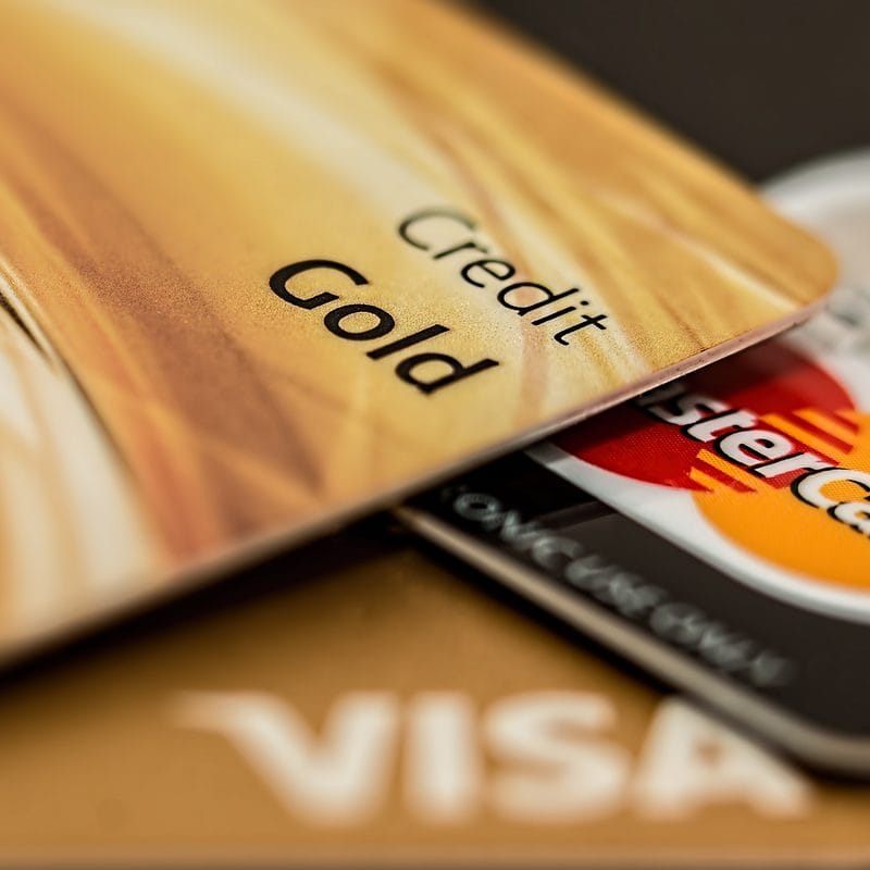 Close-up of gold credit card with part of Mastercard and Visa logos visible.