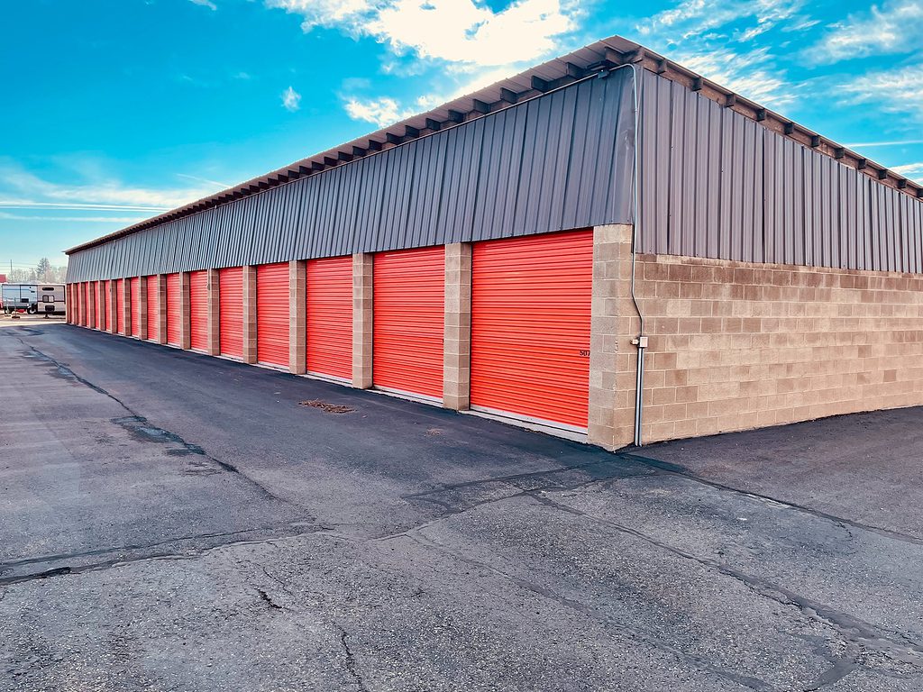 Row of red storage unit doors at a self-storage facility with clear sky