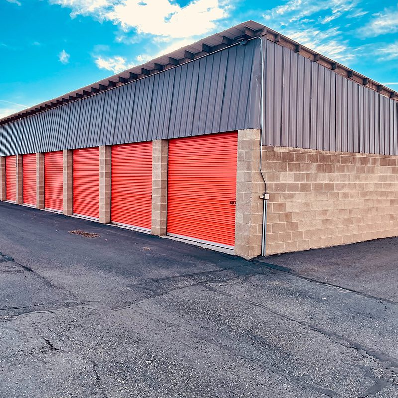 Row of red storage unit doors at a self-storage facility with clear sky