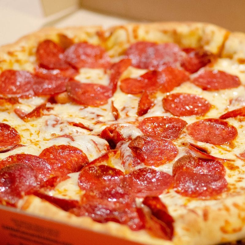 Pepperoni pizza with melted cheese in an open box