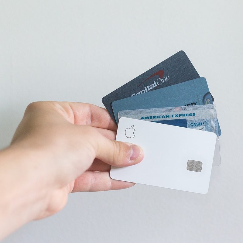 Hand holding multiple credit cards against a white background