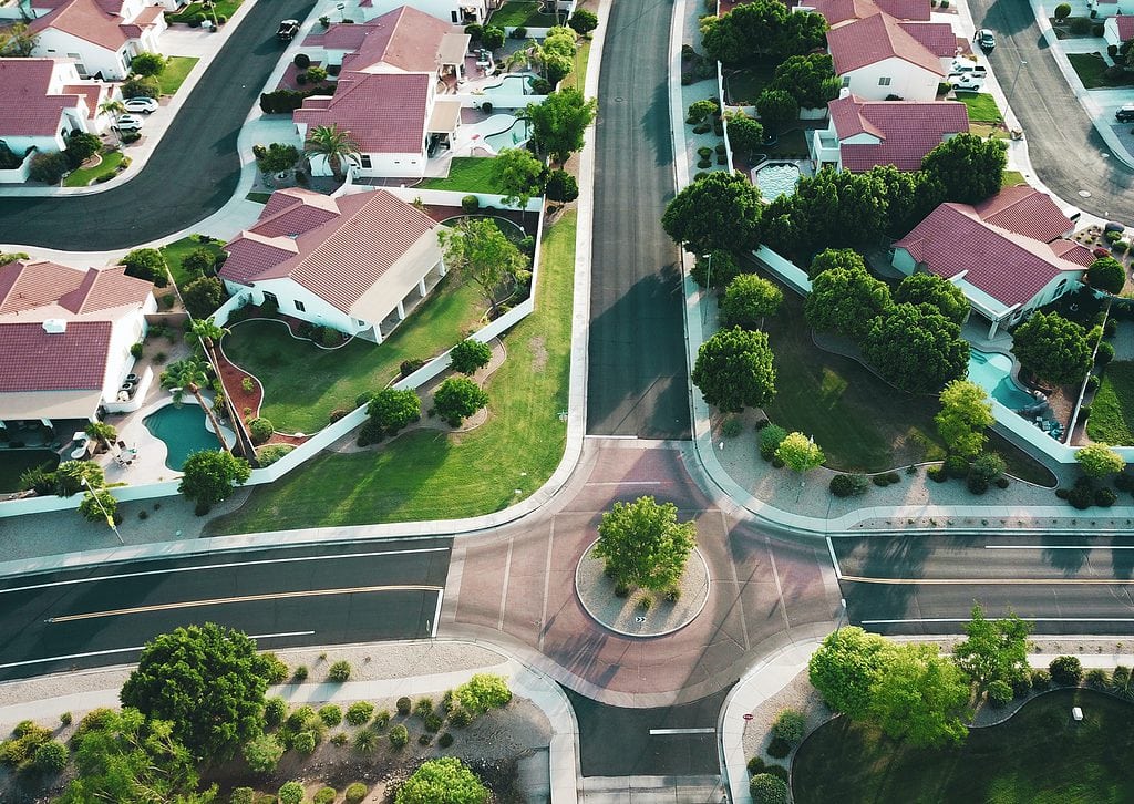 Aerial view of suburban neighborhood with red-tiled roofs and green yards