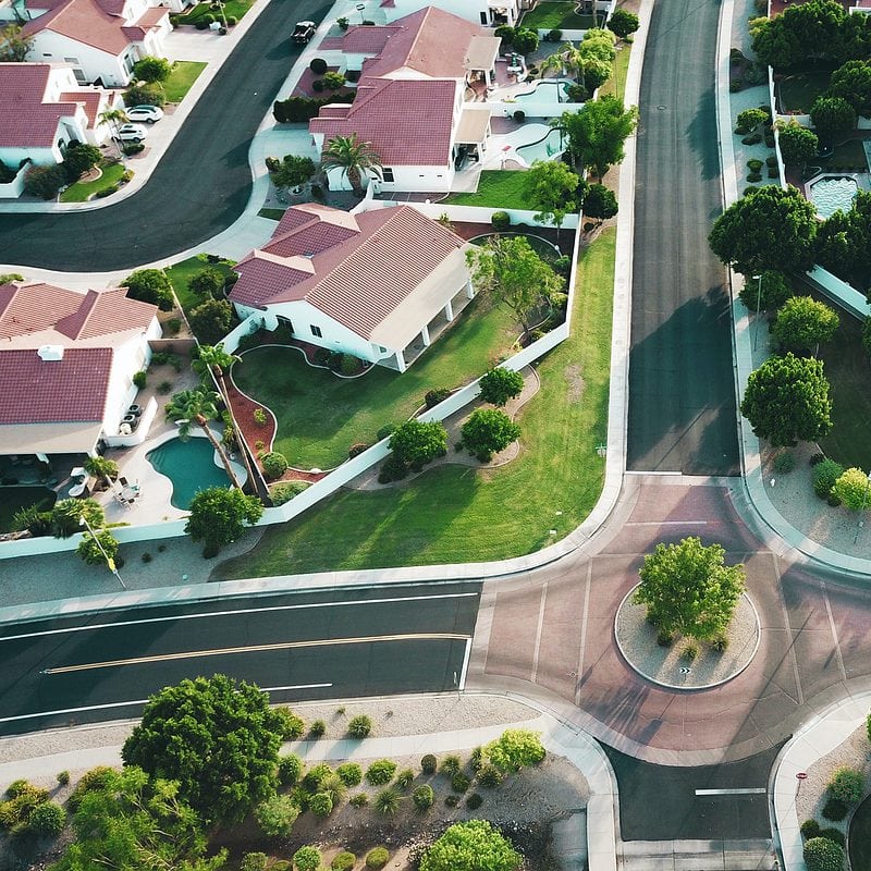 Aerial view of suburban neighborhood with red-tiled roofs and green yards