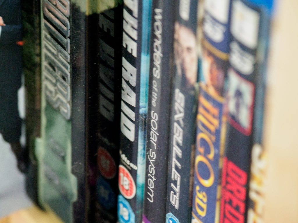 Close-up of a row of movie DVDs on a shelf with blurred titles