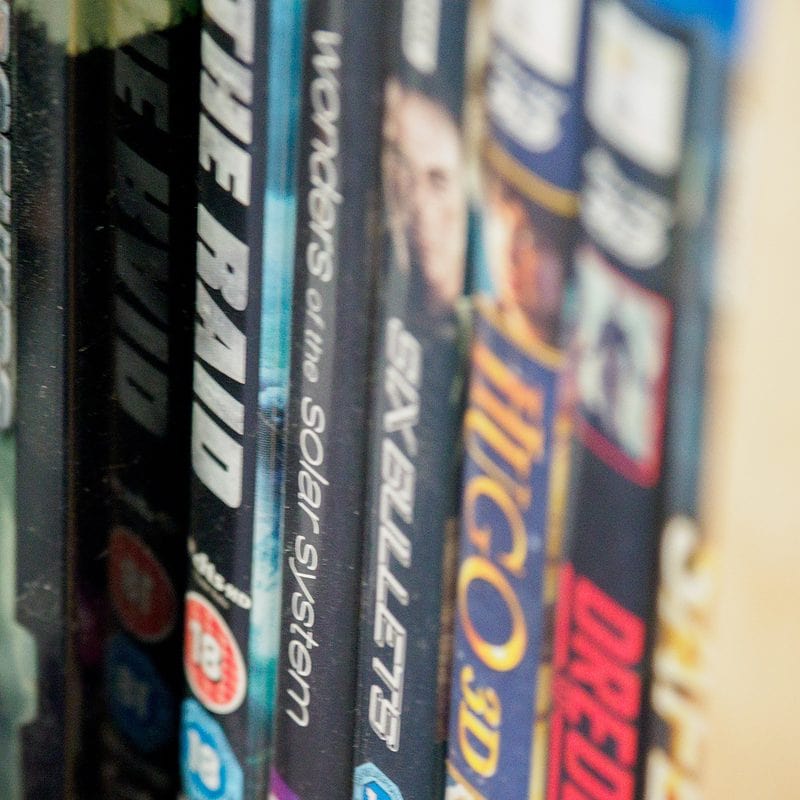Close-up of a row of movie DVDs on a shelf with blurred titles