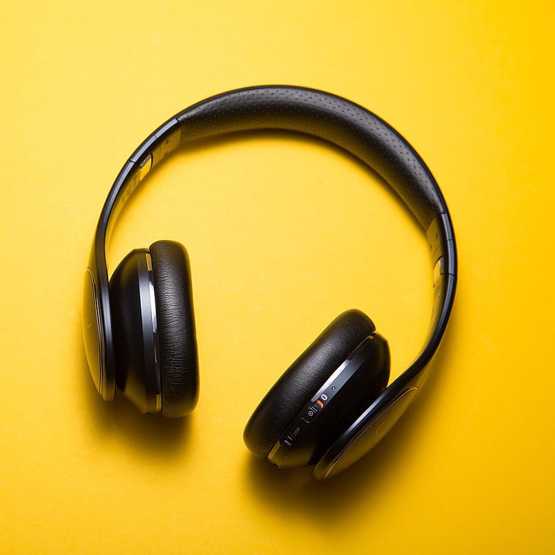 Black wireless headphones on a yellow background