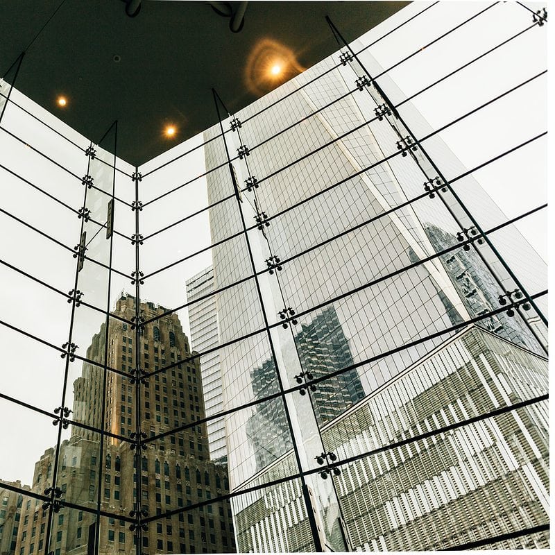 Urban skyline through glass building facade with steel cable supports