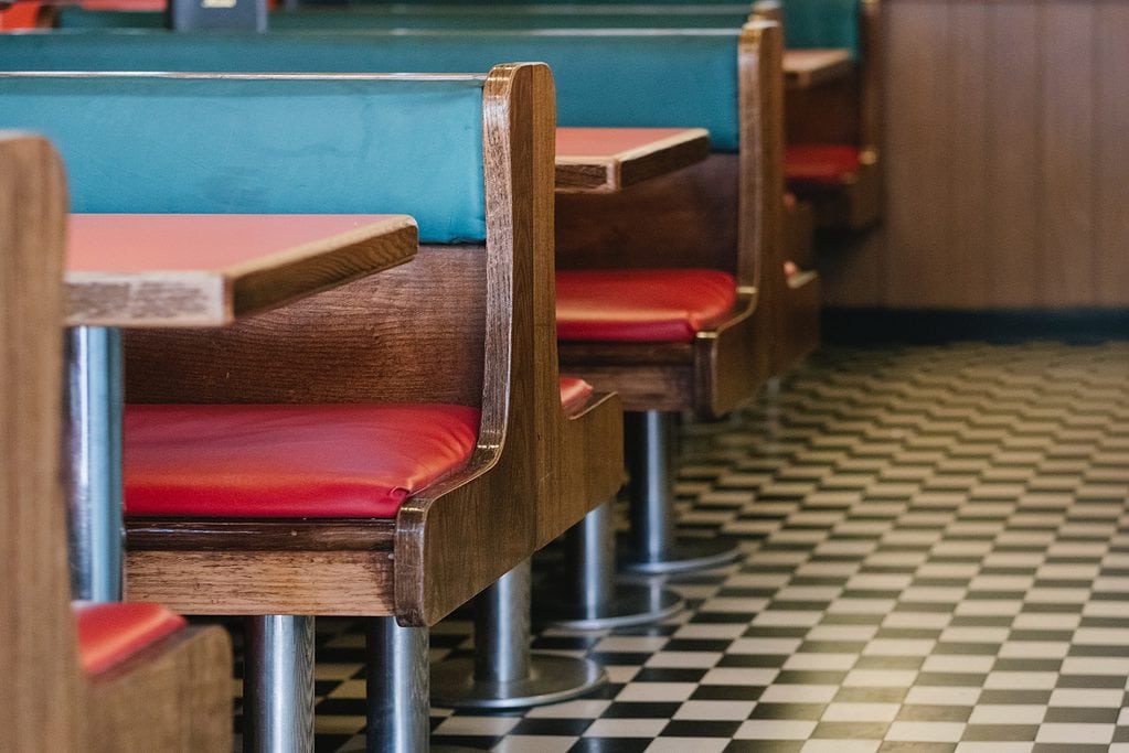 Vintage diner interior with red seats and black and white checkered floor.