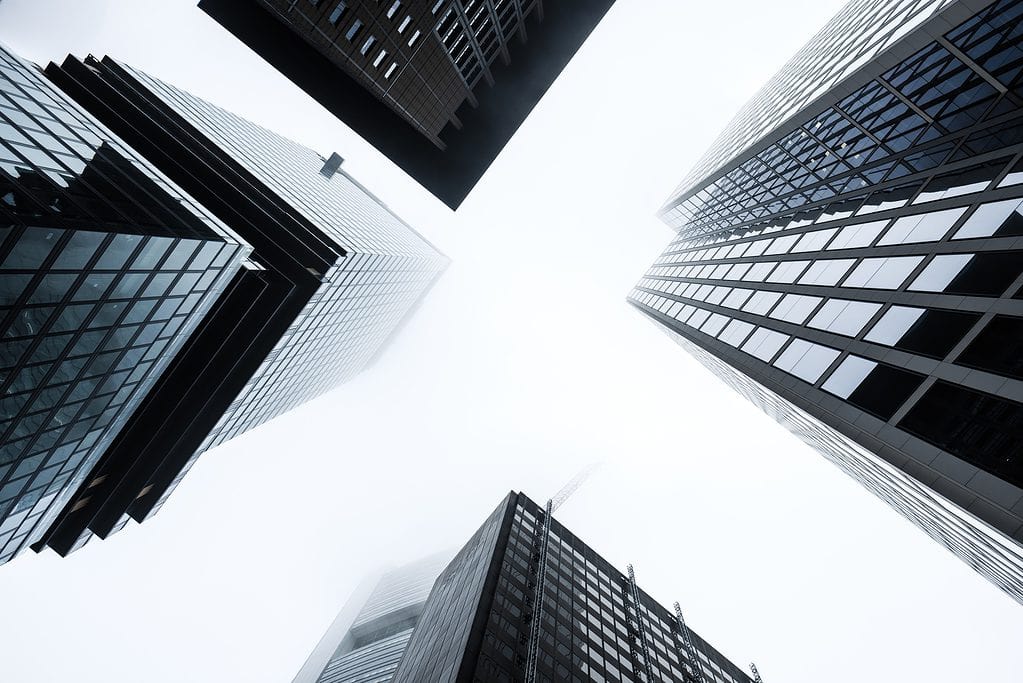 Looking up at towering skyscrapers vanishing into a foggy sky