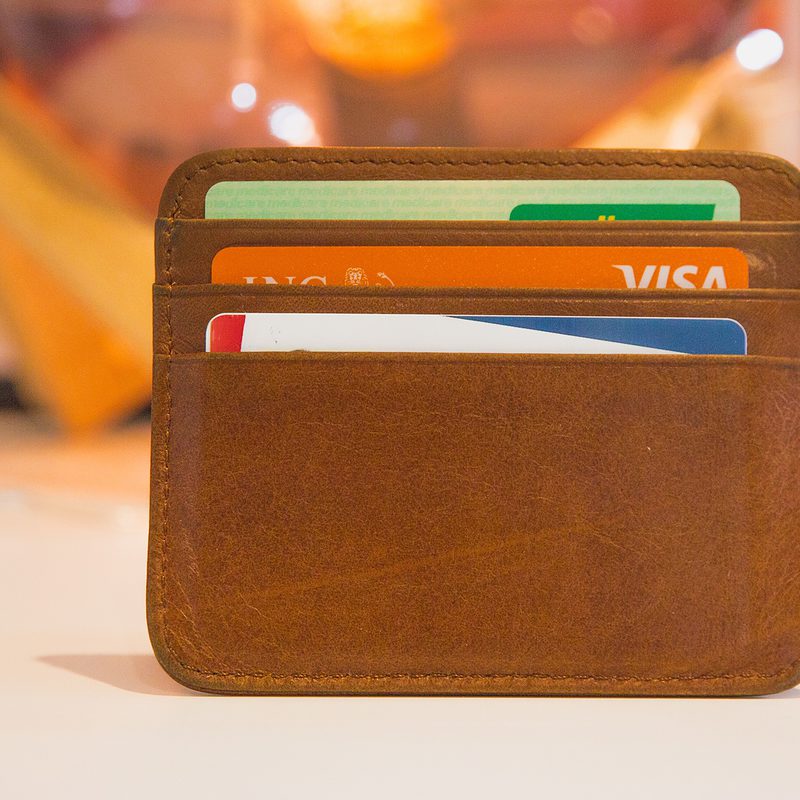 Brown leather wallet with credit cards visible against a blurred background