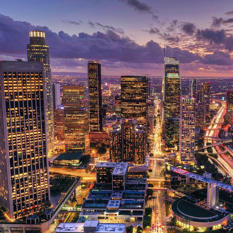 Aerial view of downtown skyscrapers at sunset with illuminated streets