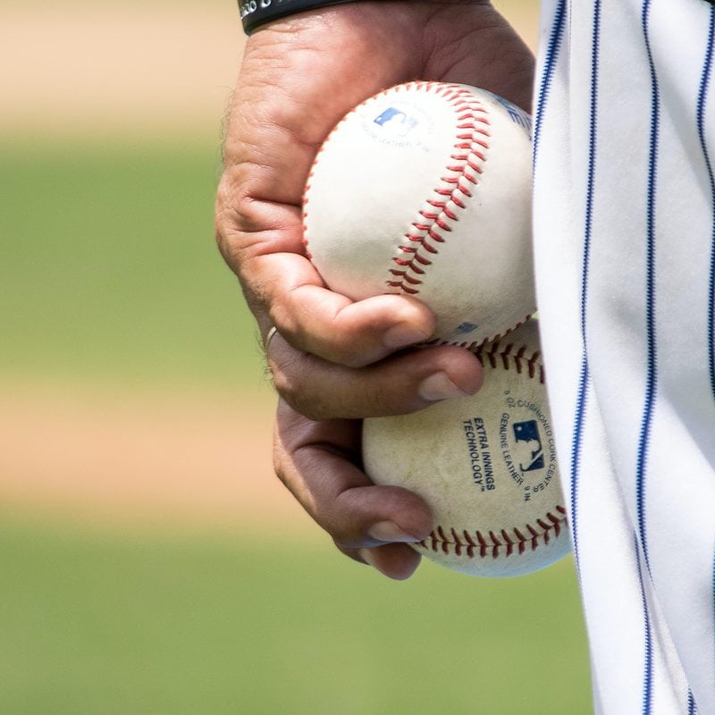 Close-up of a hand holding a baseball with a blurred background
