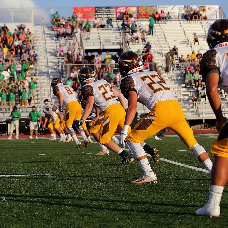 High school football team on field with spectators in stands