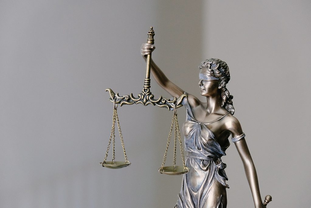 Bronze Lady Justice statue with scales on grey background