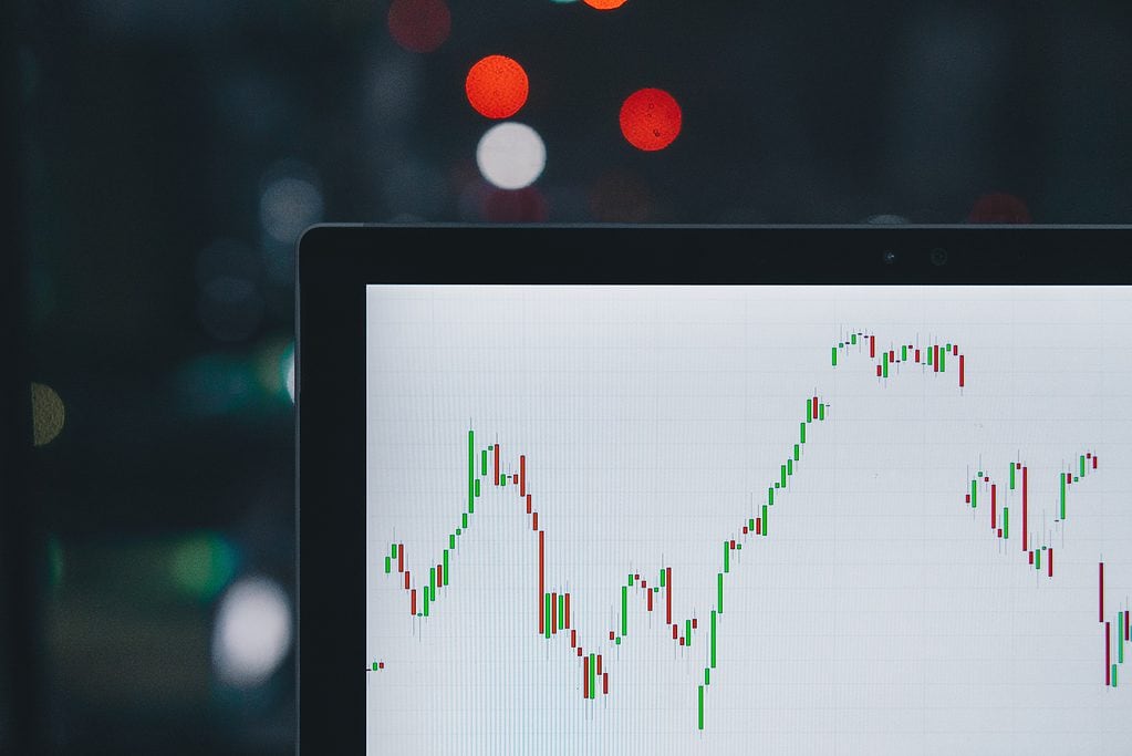 Laptop screen displaying stock market chart with bokeh lights in background