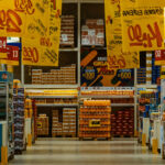 Supermarket aisle with various products and colorful discount signs.