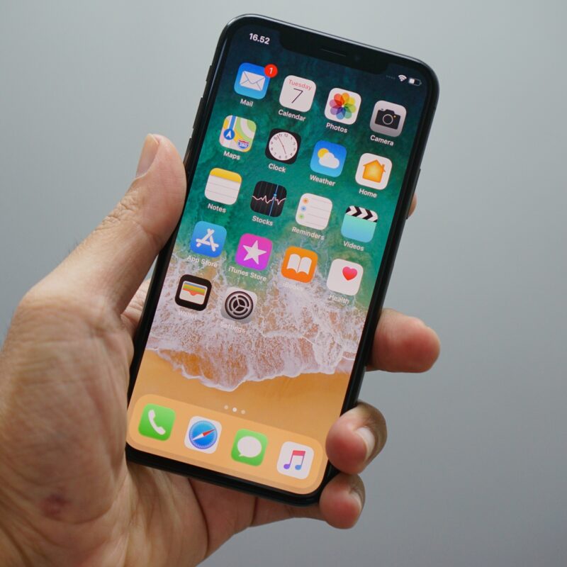 Hand holding a smartphone with colorful app icons on screen